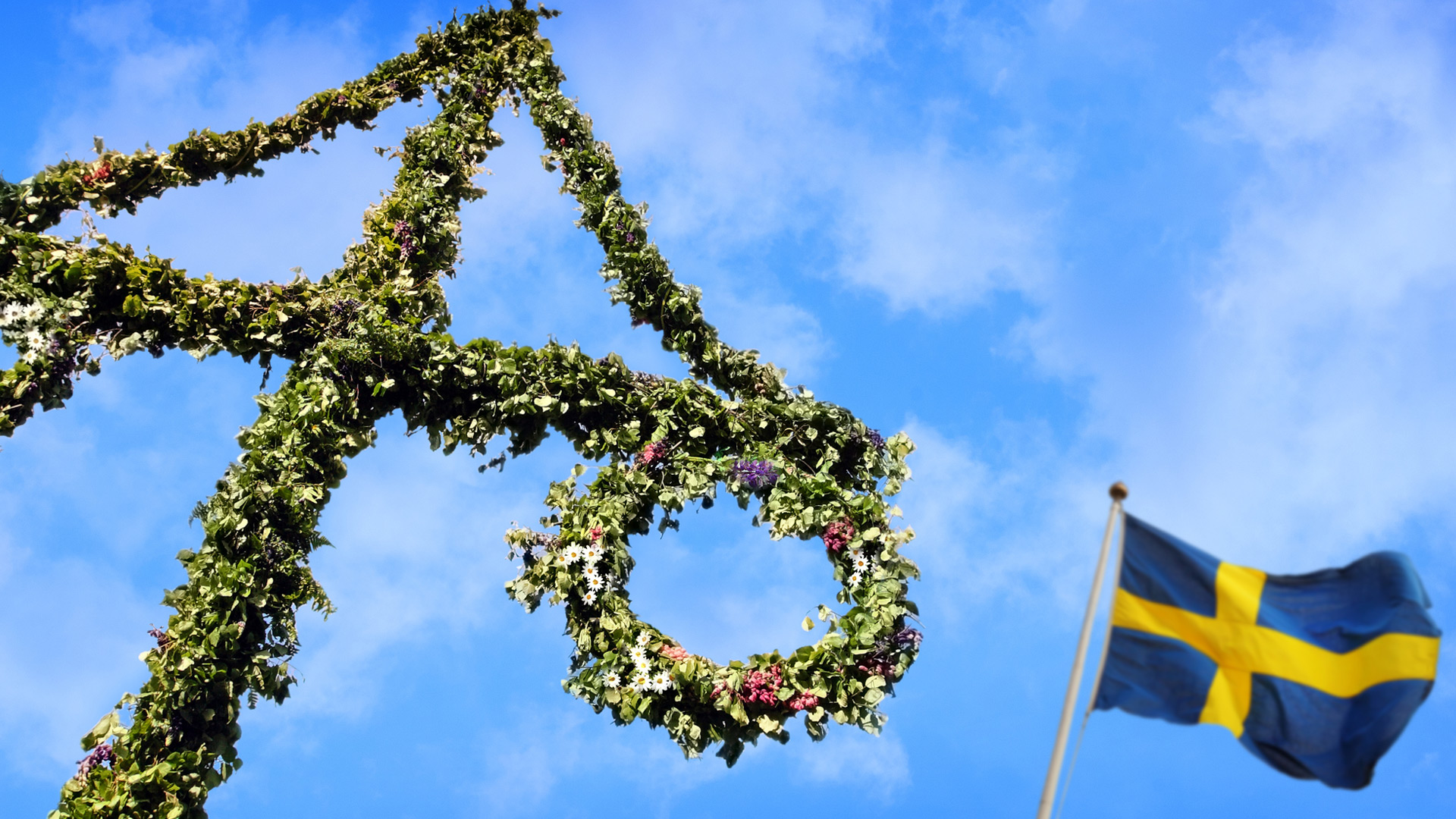 Midsummer pole and Swedish flag against a blue sky